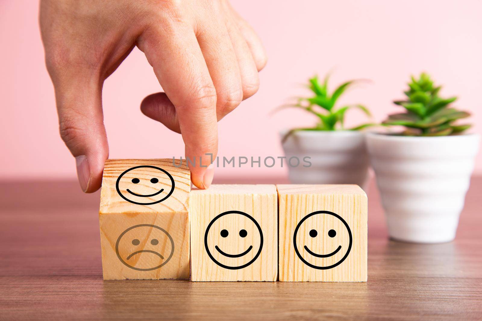 Customer service evaluation and satisfaction survey concepts. The client's hand turned the happy face smile on wooden blocks, copy space