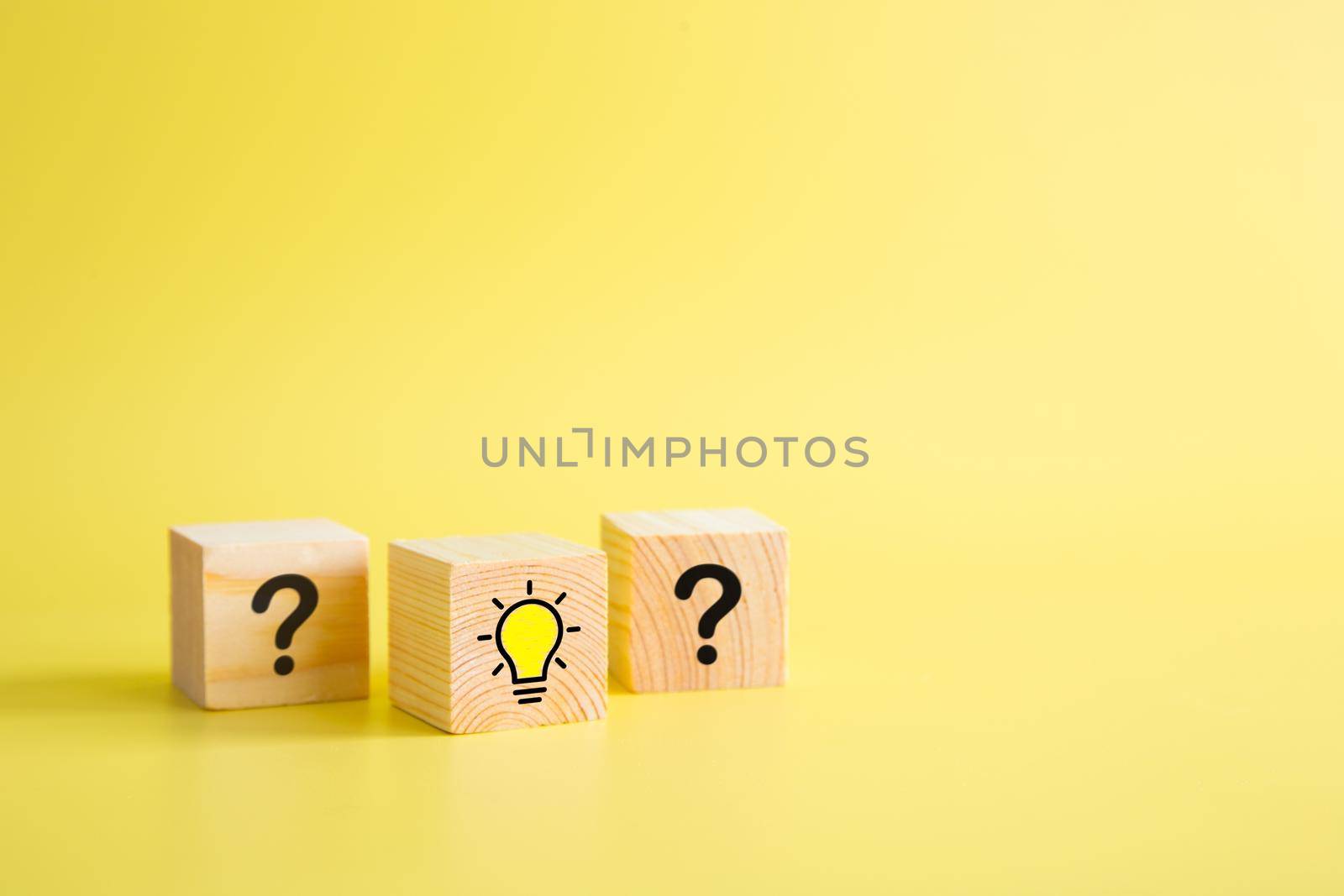 Lightbulb icon and question mark print screen on wooden block cube. It is creative thinking idea and innovation concept.