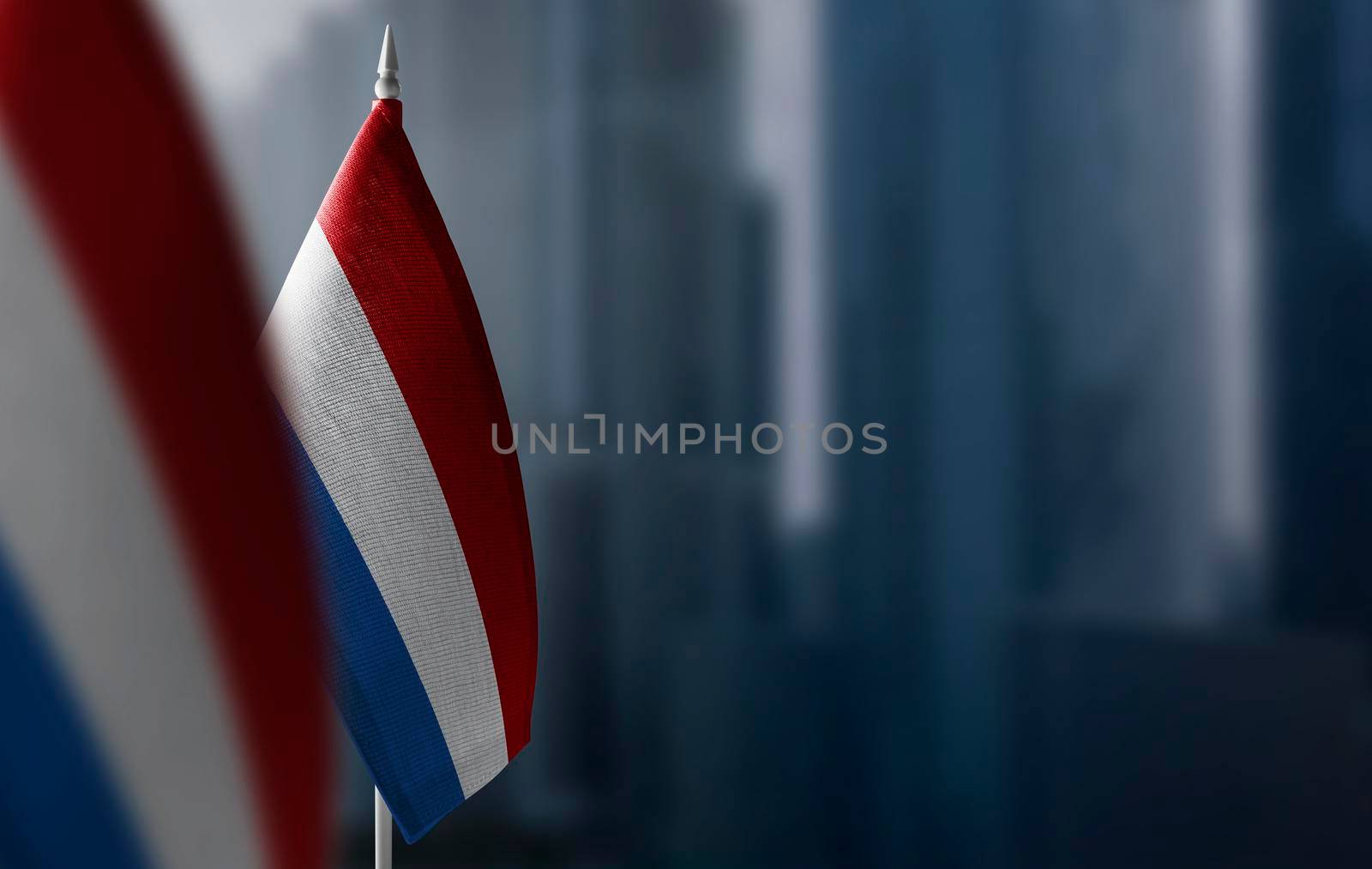 Small flags of Netherlands on a blurry background of the city.