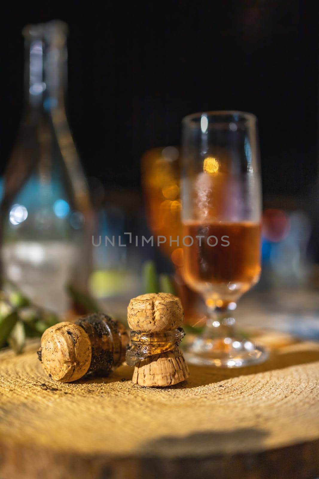 Glass of champagne with two broken corks lay on wooden board on table