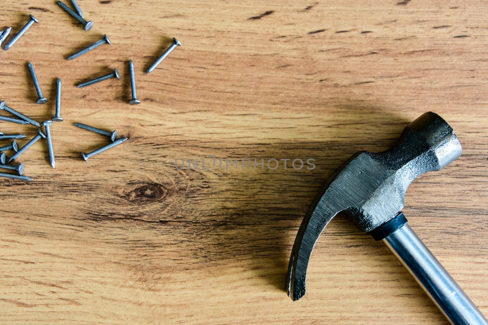 Metal hammer with nails on a wooden table. Close up. Carpenter concept. Copy space.
