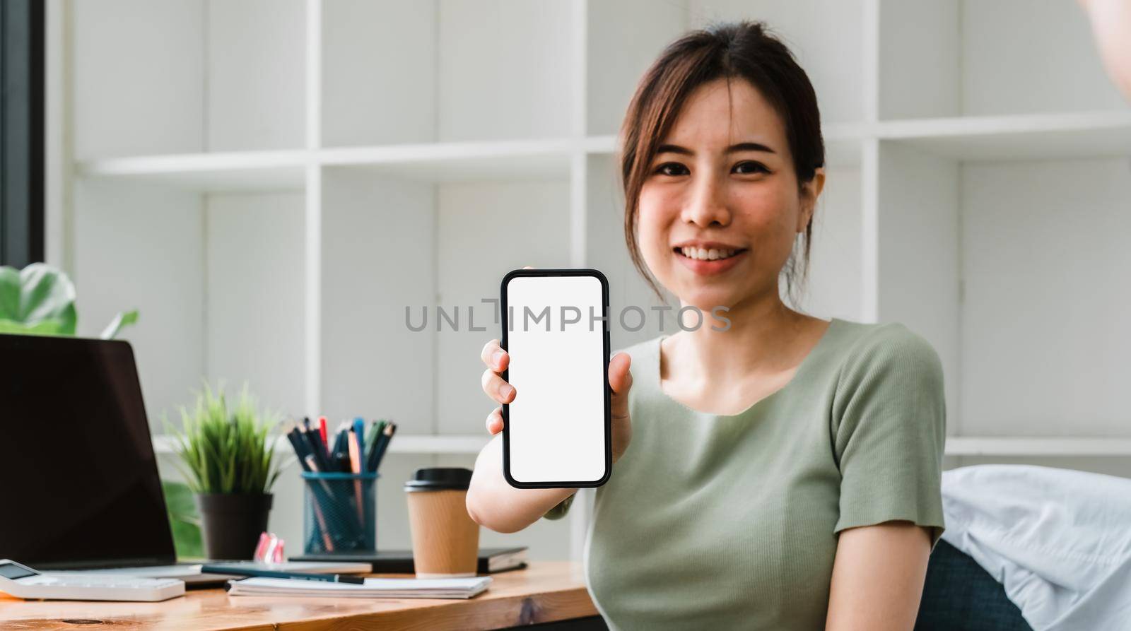 Beautiful asian woman showing mobile phone with blank white screen at her office. business accounting financial.