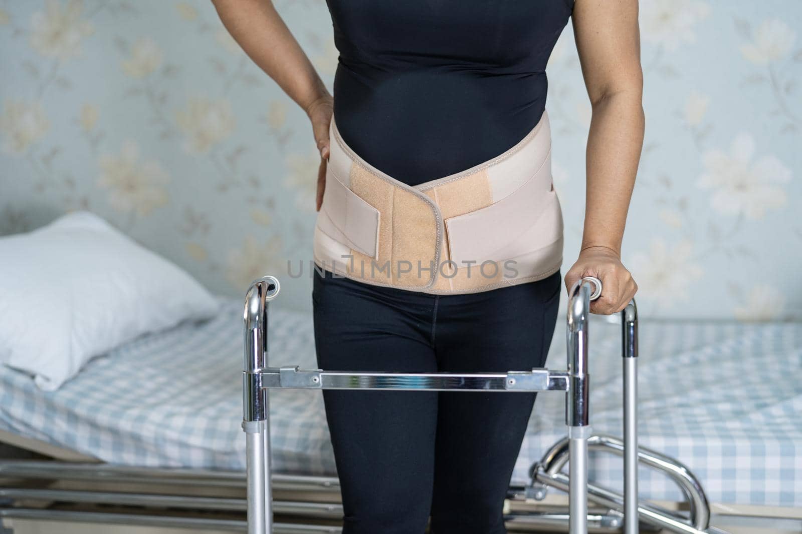 Asian lady patient wearing back pain support belt for orthopedic lumbar with walker.