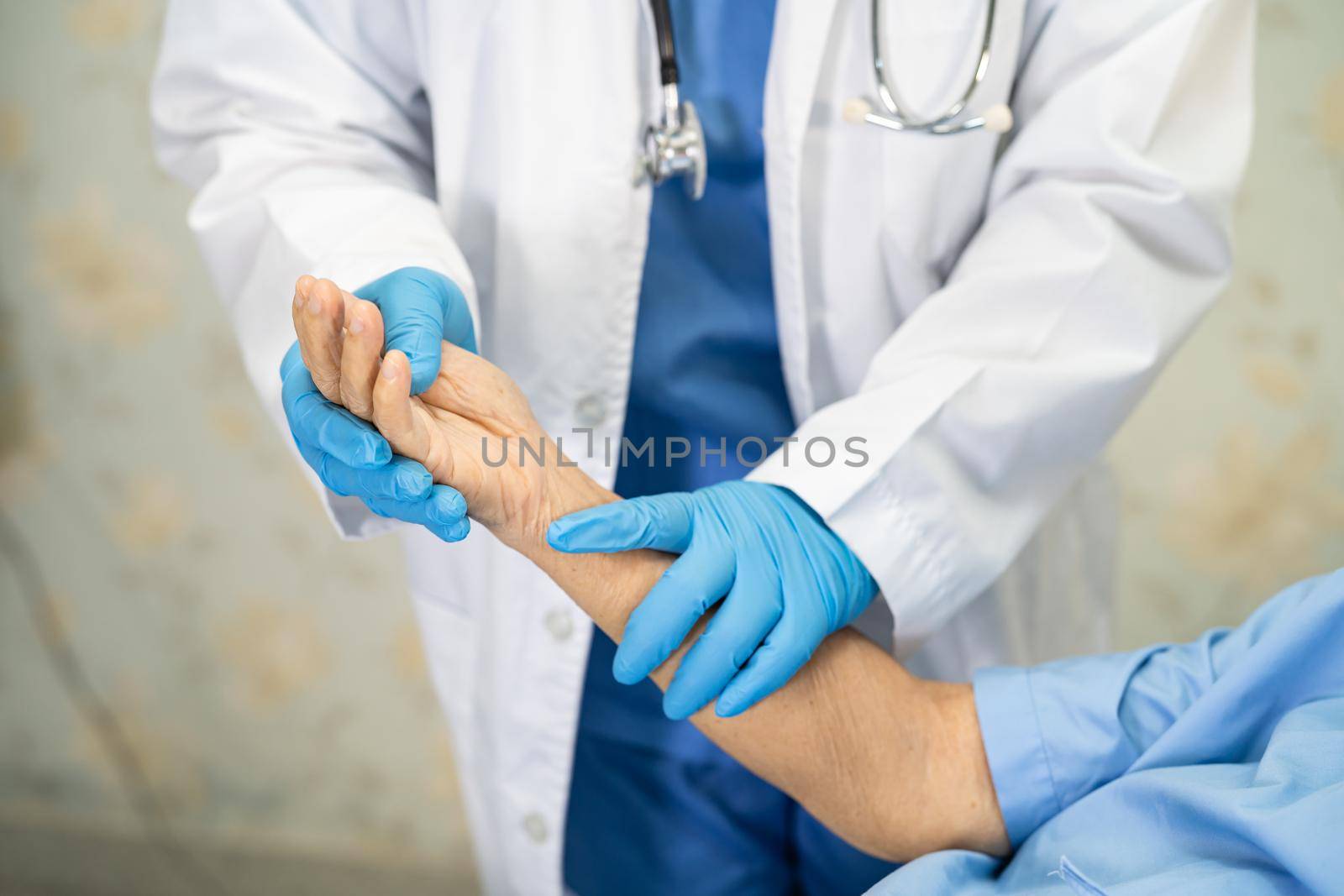 Doctor using stethoscope to checking Asian senior or elderly old lady woman patient wearing a face mask in hospital for protect infection Covid-19 Coronavirus. by pamai