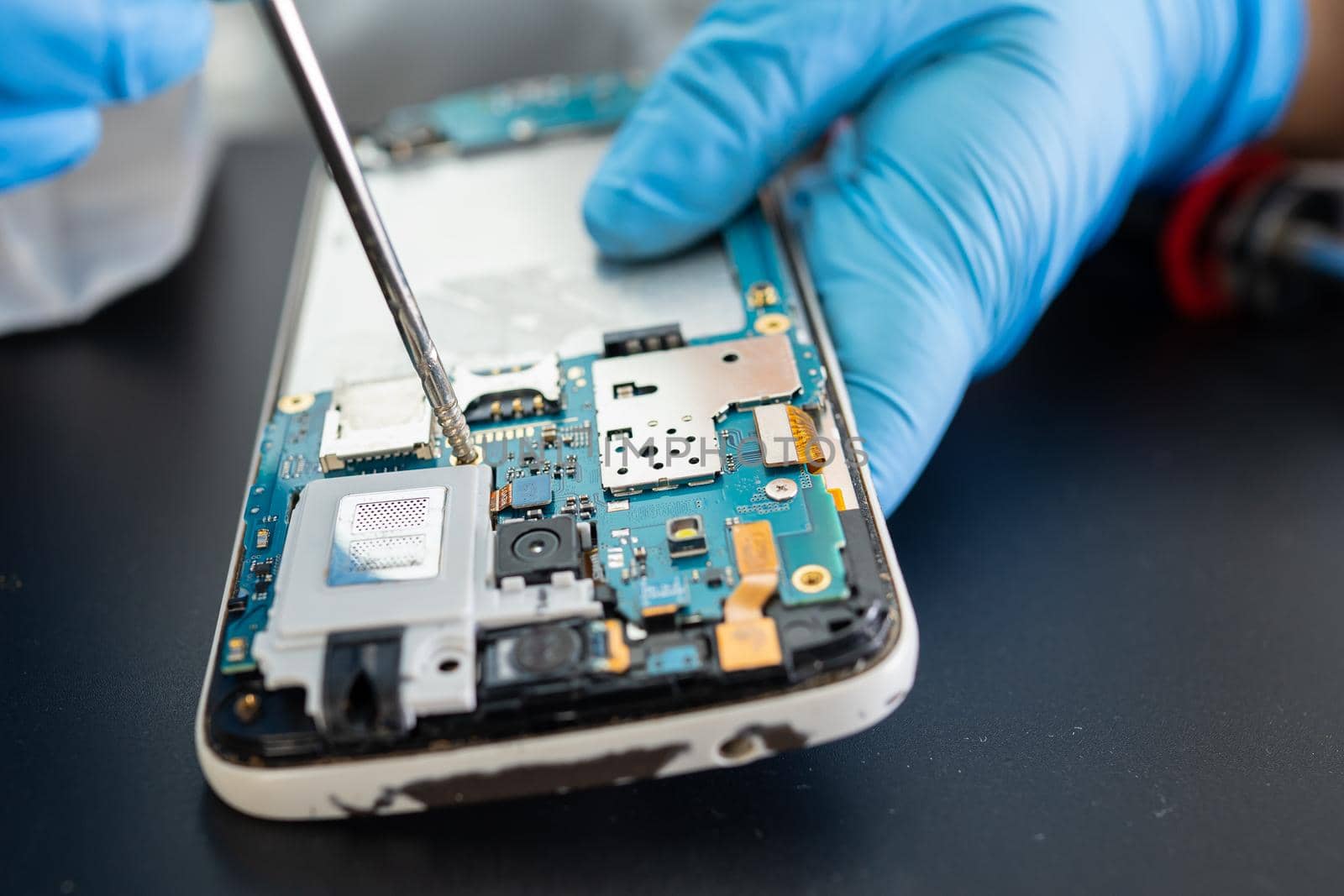 Technician repairing inside of mobile phone by soldering iron. Integrated Circuit. the concept of data, hardware, technology.