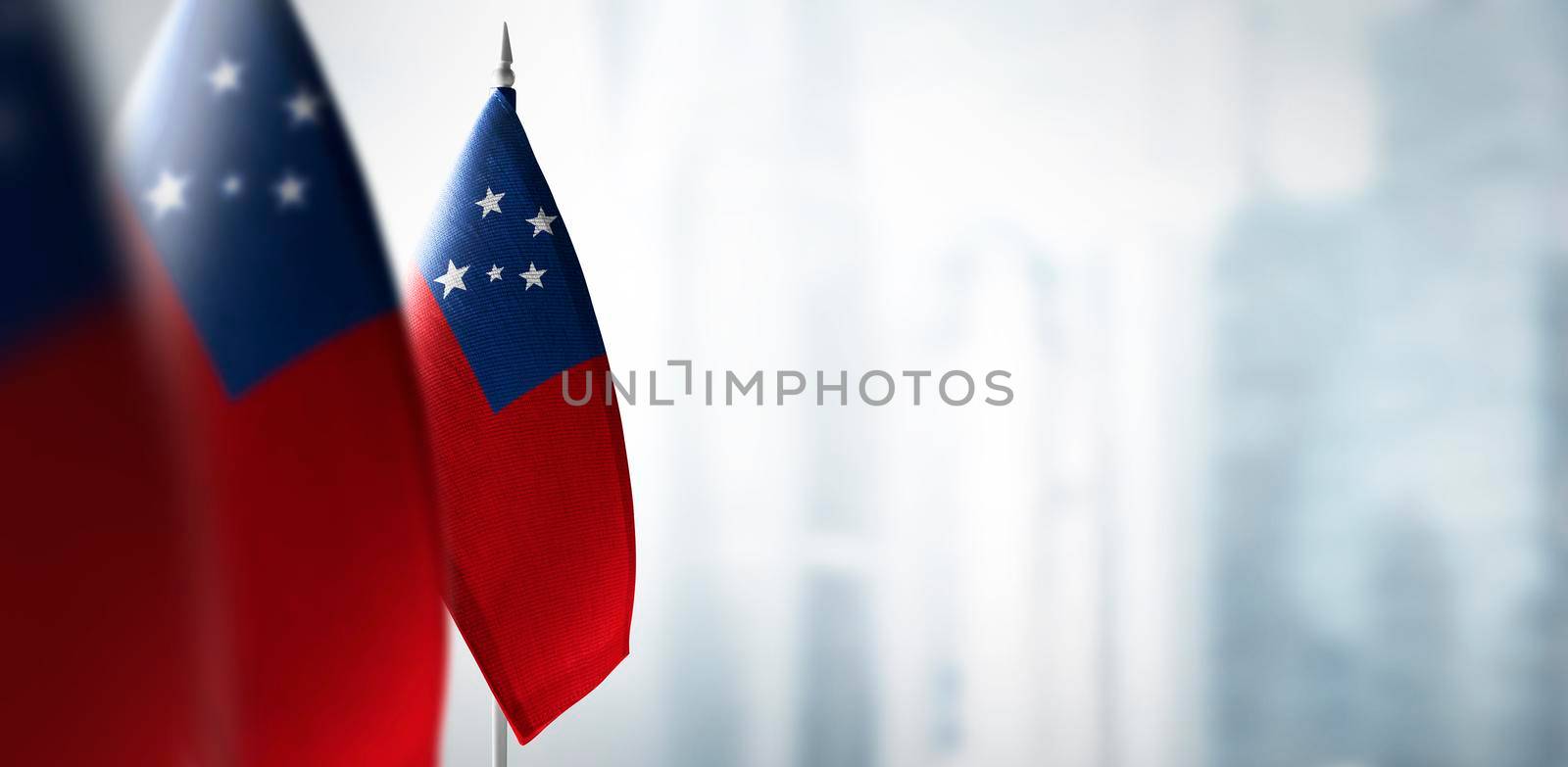 Small flags of Samoa on a blurry background of the city by butenkow