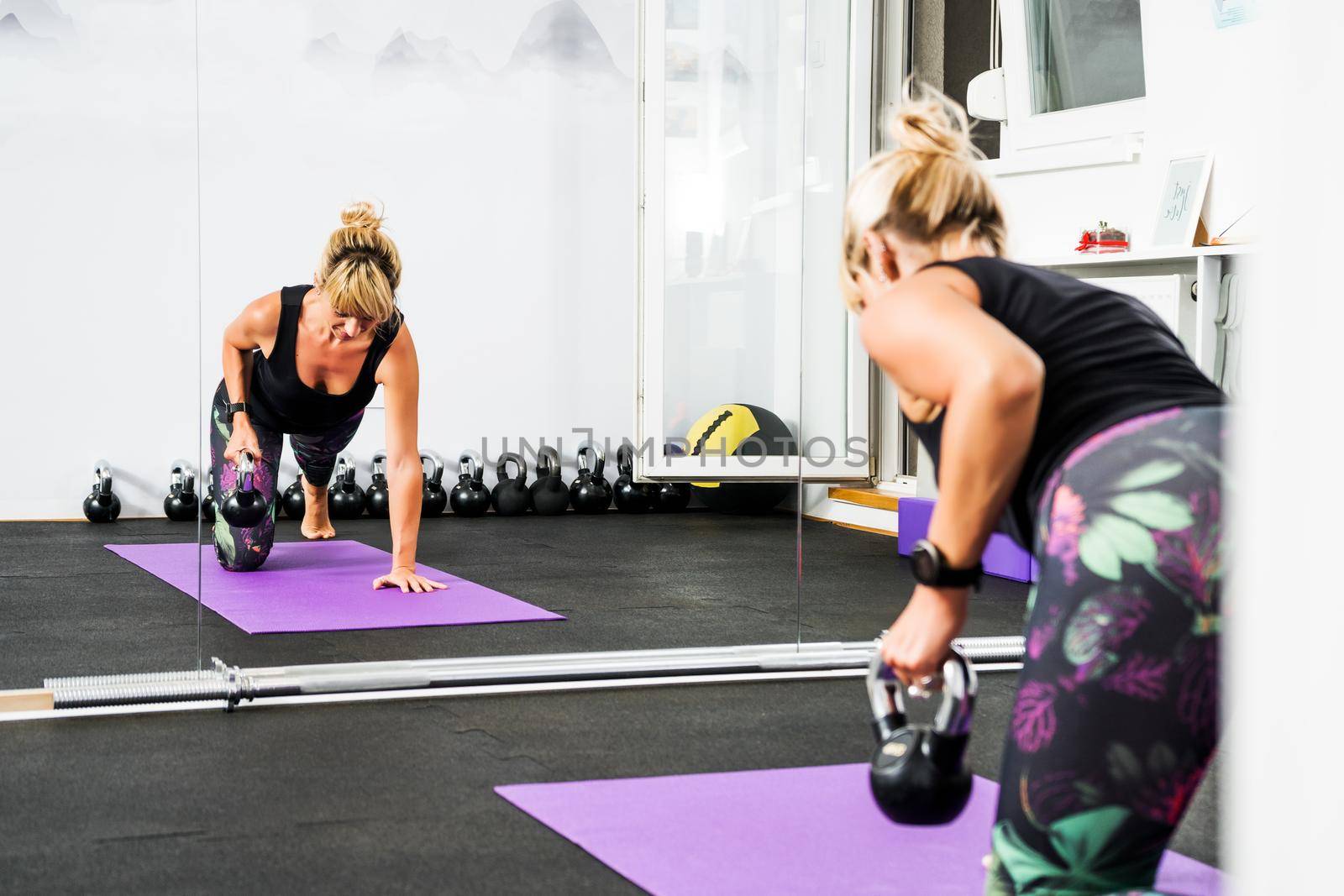 Beautiful woman is practicing kettlebell pilates in gym.