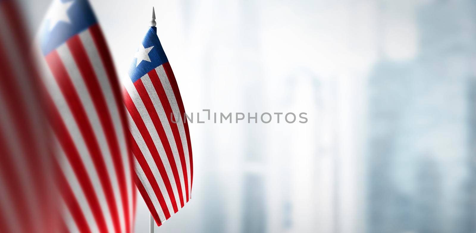 Small flags of Liberia on a blurry background of the city by butenkow