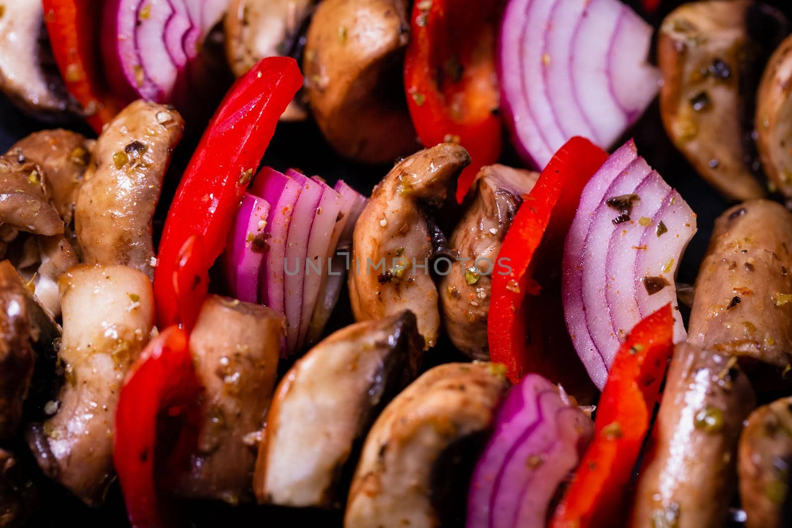 Close up of mushroom, red onion and red peppers kebabs