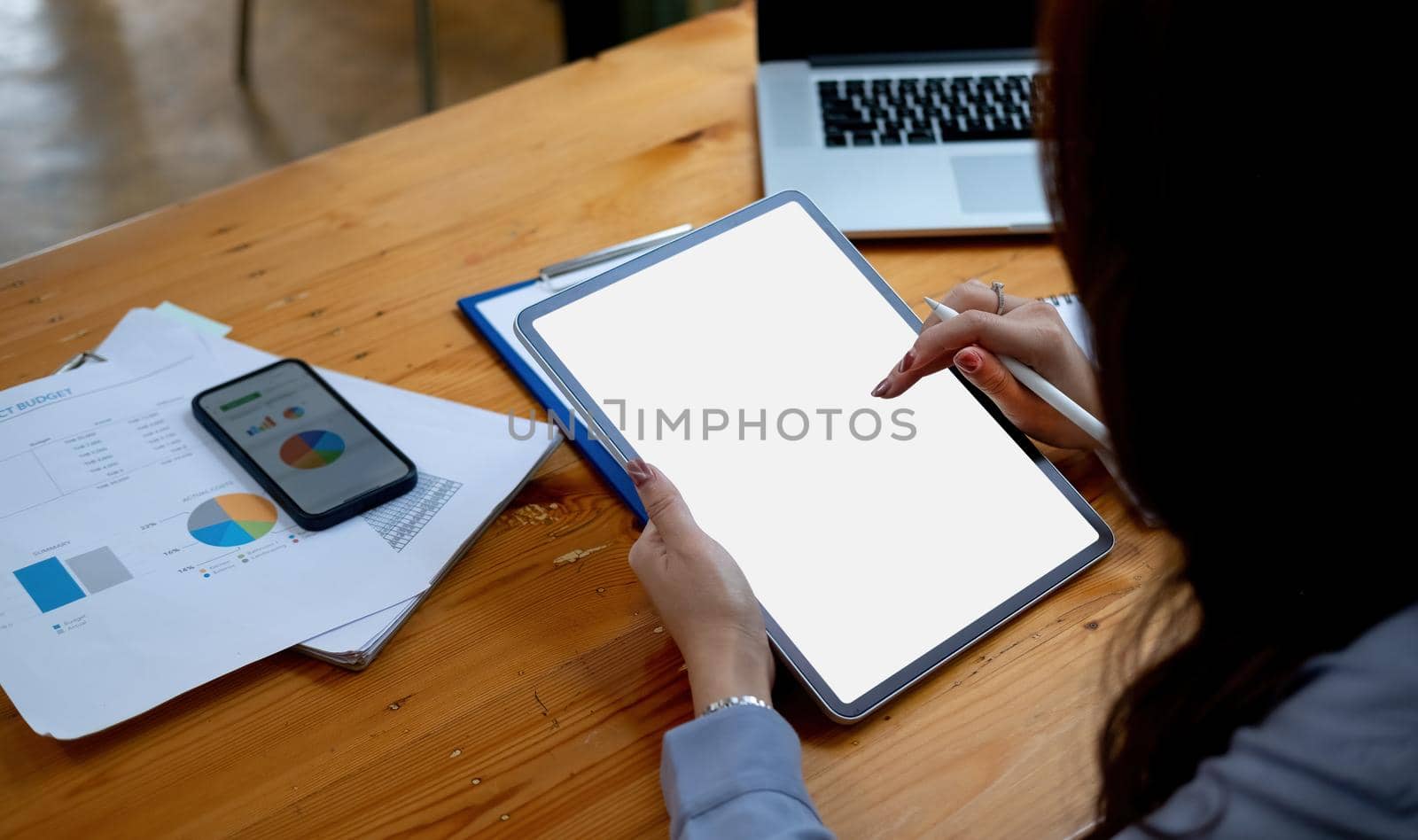 businesswoman holding a pen to use a tablet blank white screen in office working. Mock up. business financial concept.