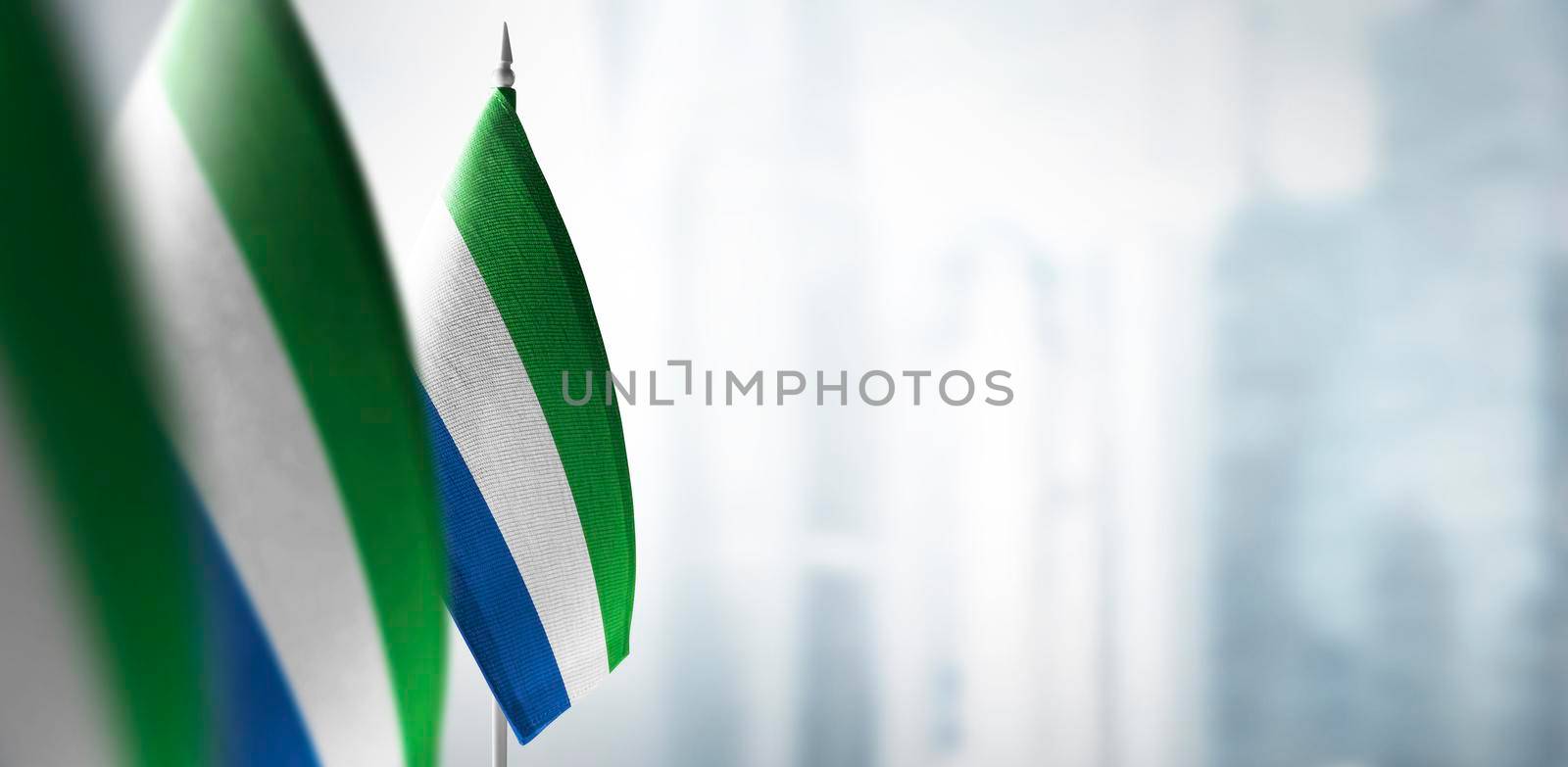 Small flags of Sierra Leone on a blurry background of the city.