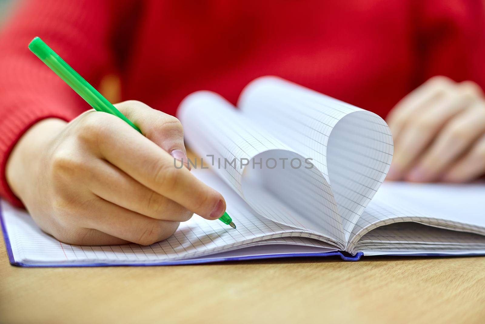 female hand writing on a blank piece heart-shaped Notepad with pen