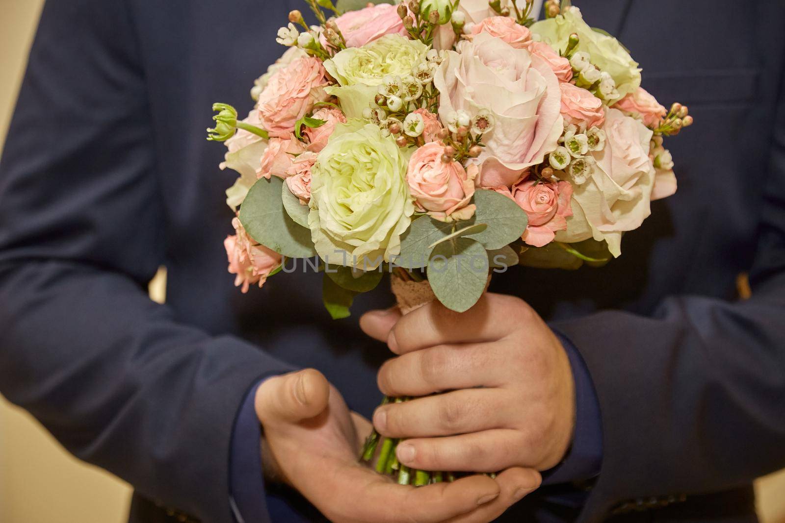 Stylish groom holds wedding bouquet. Young groom in a suit. Groom in classic clothes with bow tie