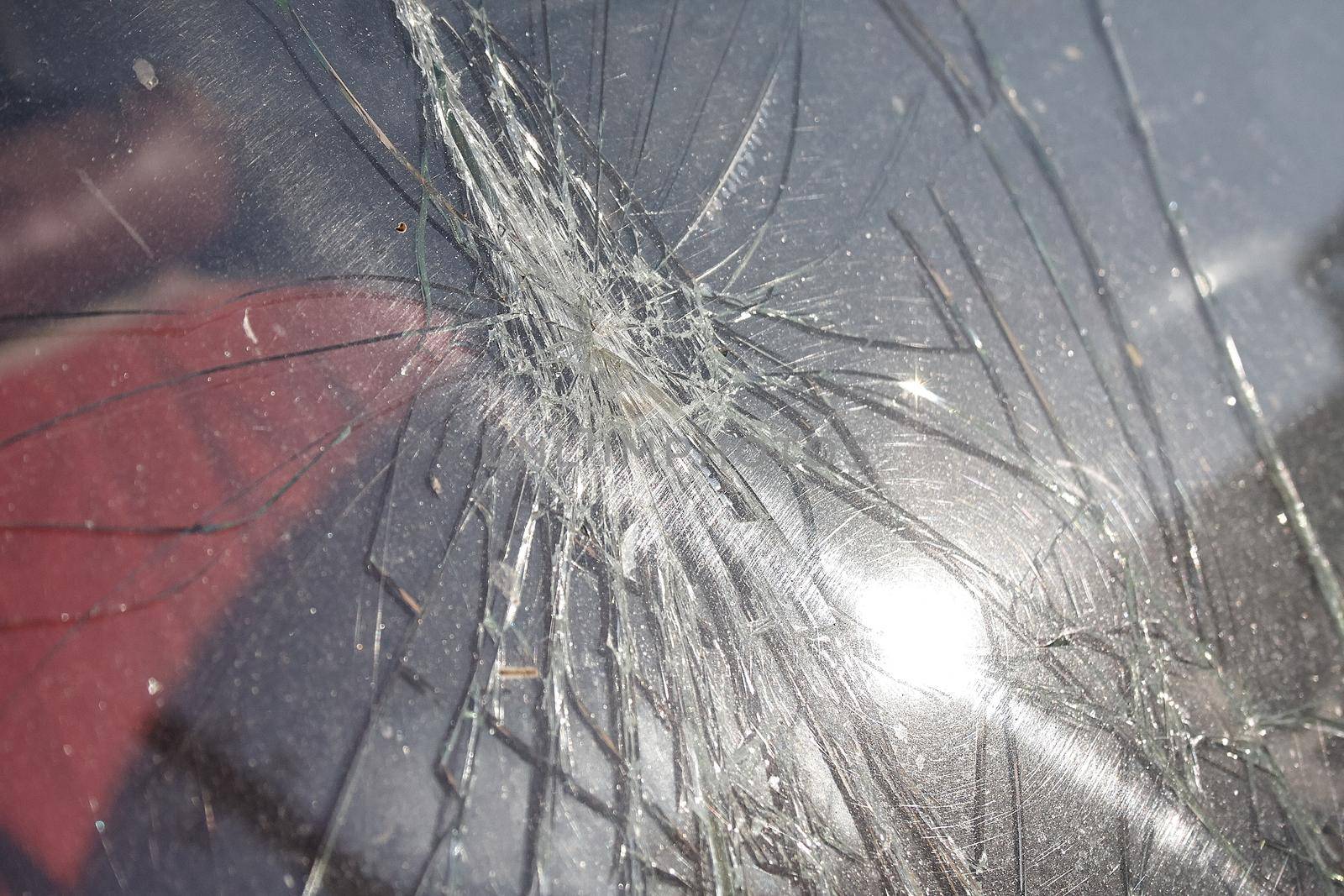Cracks and glass shards radiate from the point of impact in a window that has been hit by an object