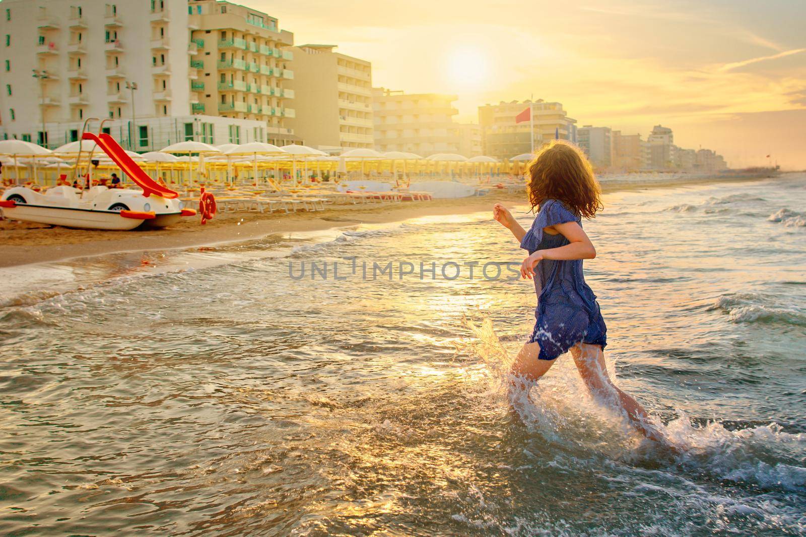 baby girl in a striped dress and runs to the sea the ocean