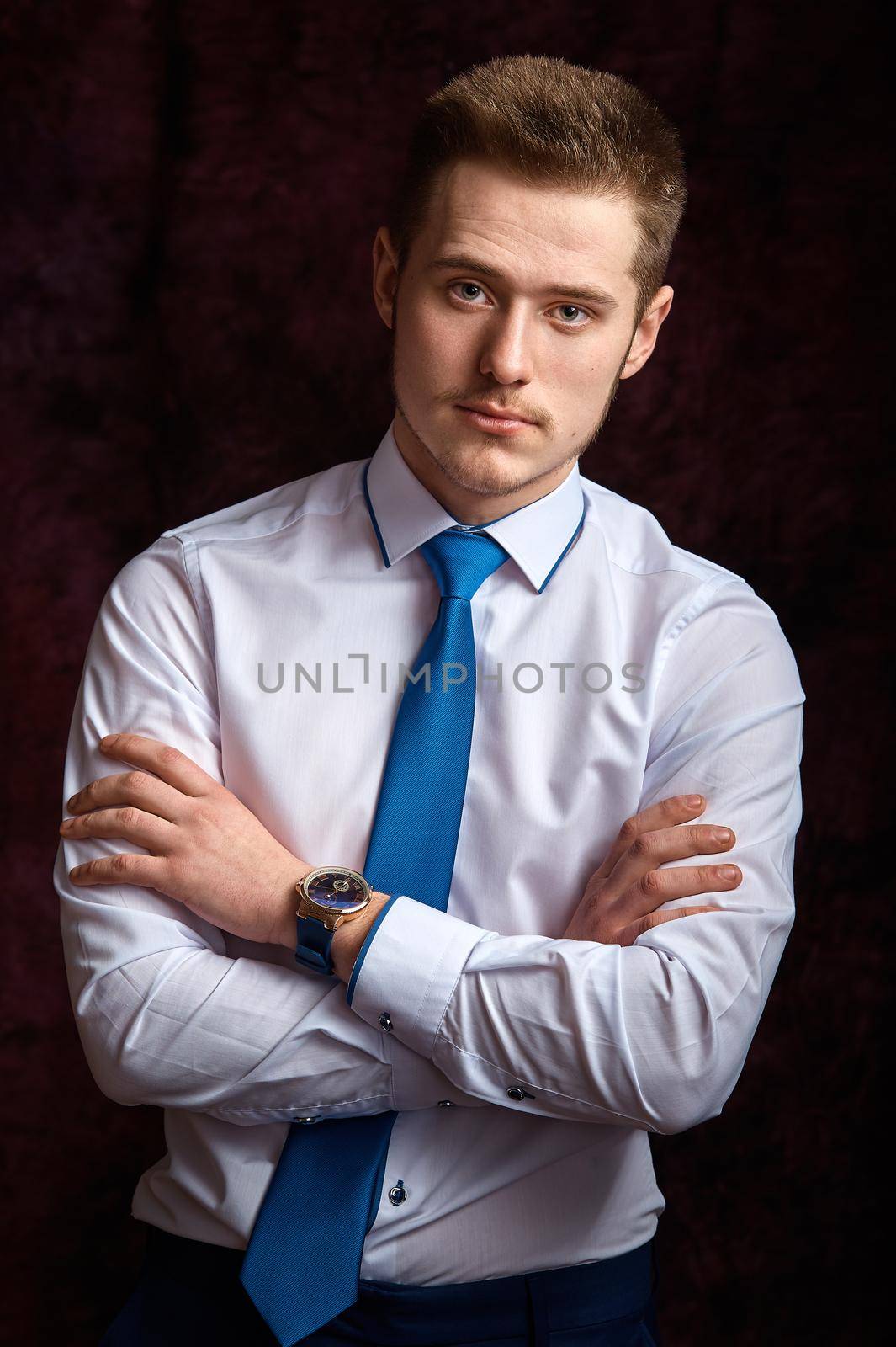 Portrait of a smart serious young man standing on dark background