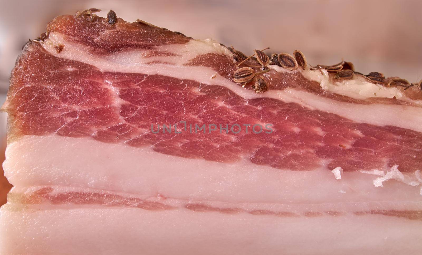 Raw pork brisket with caraway seeds, salt and pepperlying. Salty pork brisket. Closeup