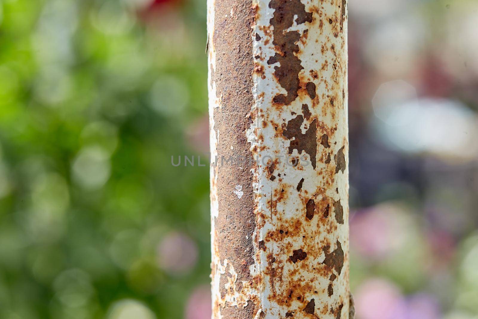 Rusty iron pole as part of a metal wire fence underneath a pier.