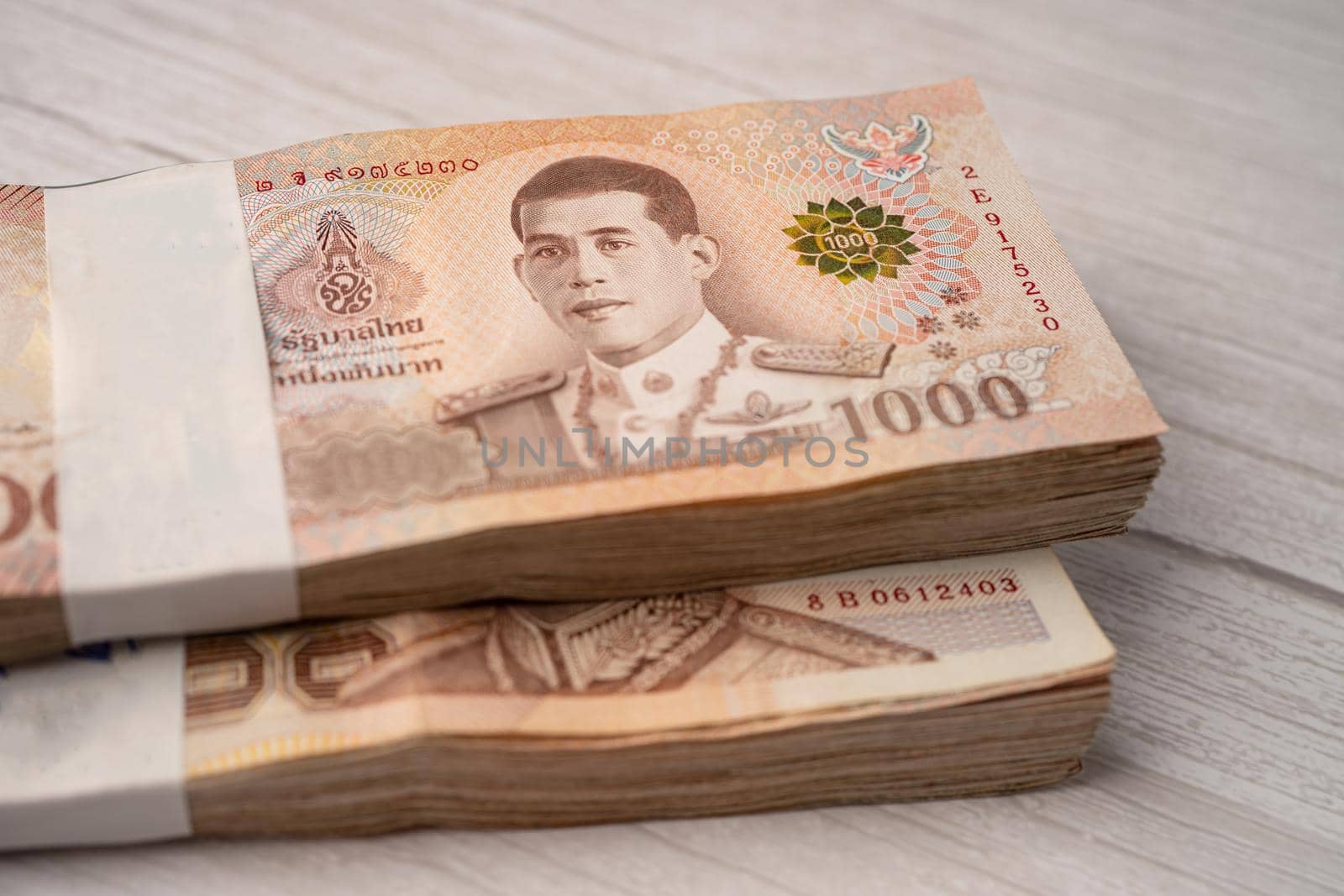 Stack of Thai baht banknotes on wooden background, business saving finance investment concept. by pamai