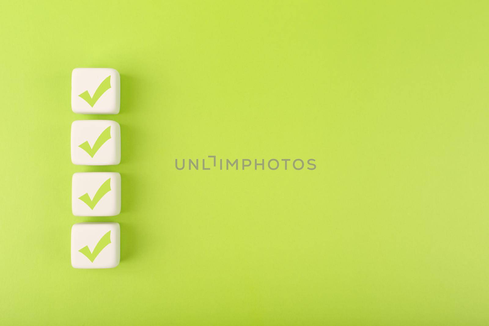 Four checkmarks on white cubes against bright green background with copy space. Concept of questionary, checklist, to do list, planning, business or verification. Creative minimal composition 