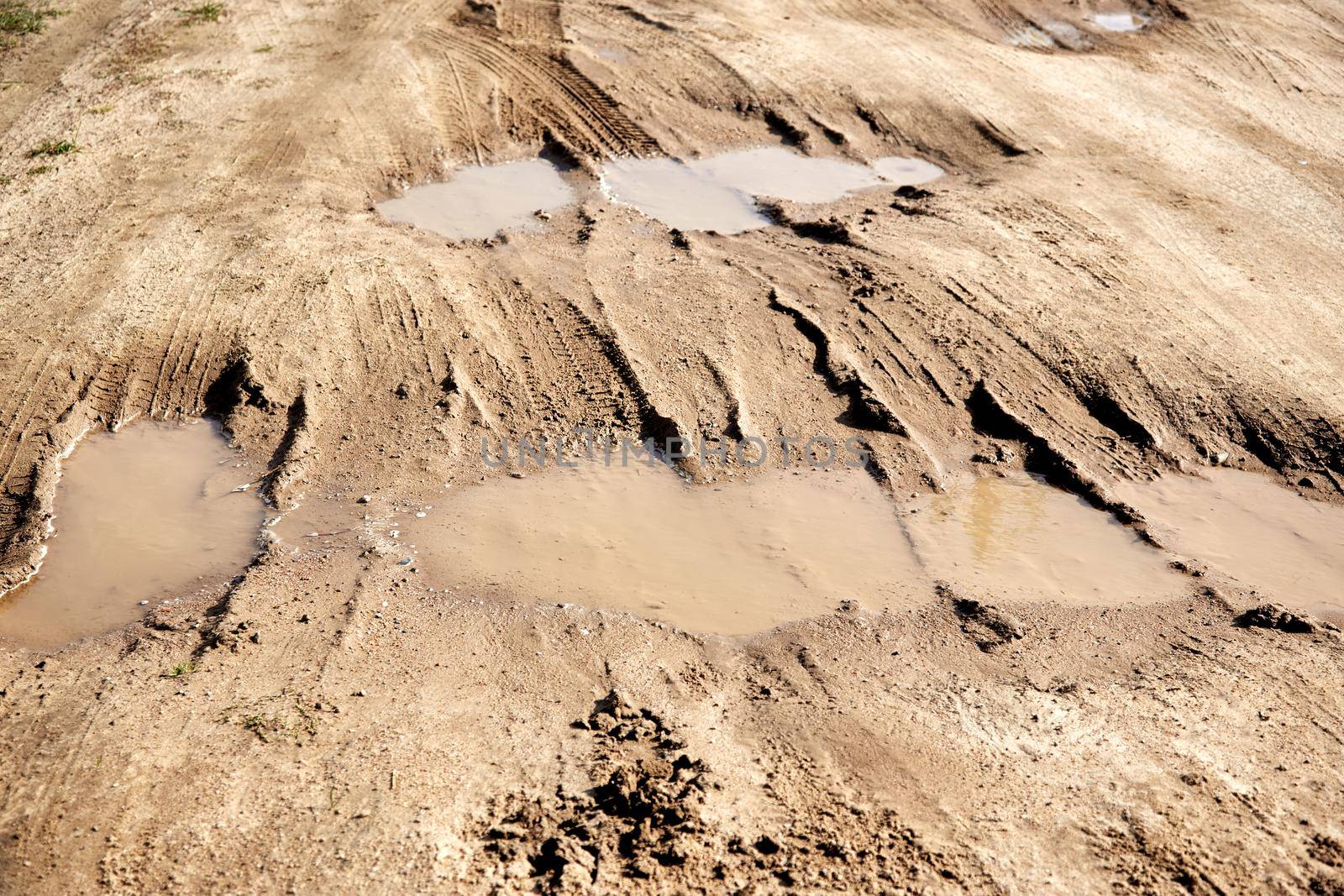 many puddles on a dirt sandy road