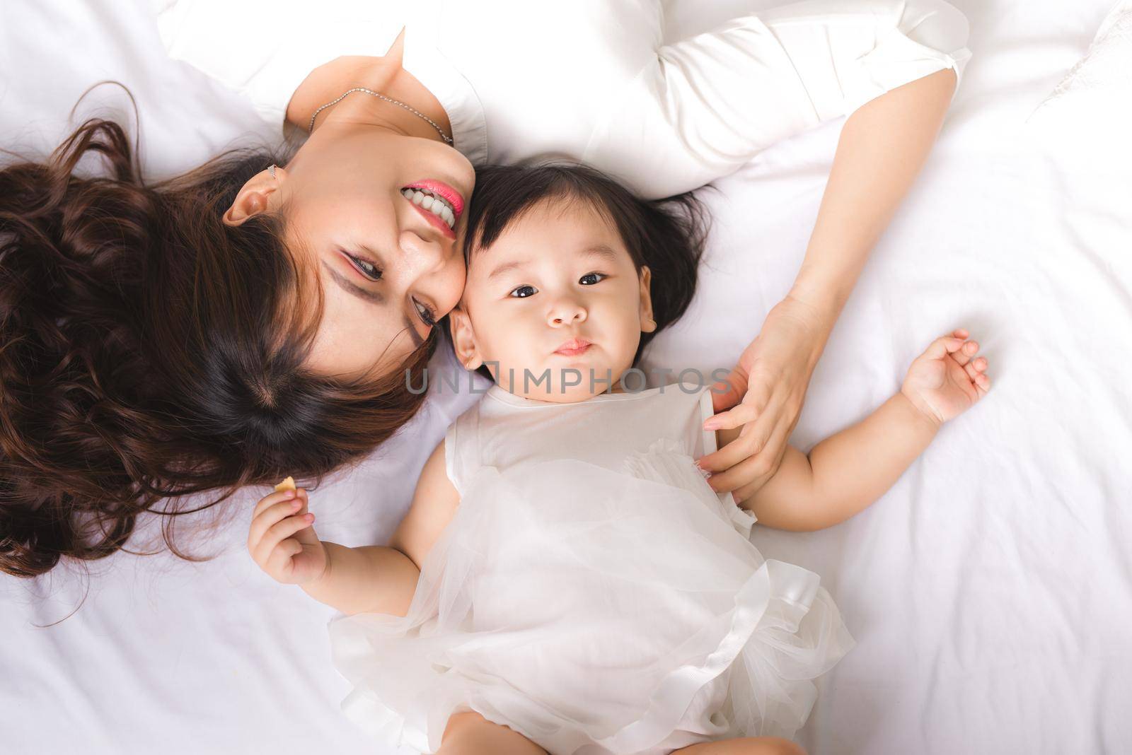 Happy loving family. Mom and child girl are having fun on the bed.