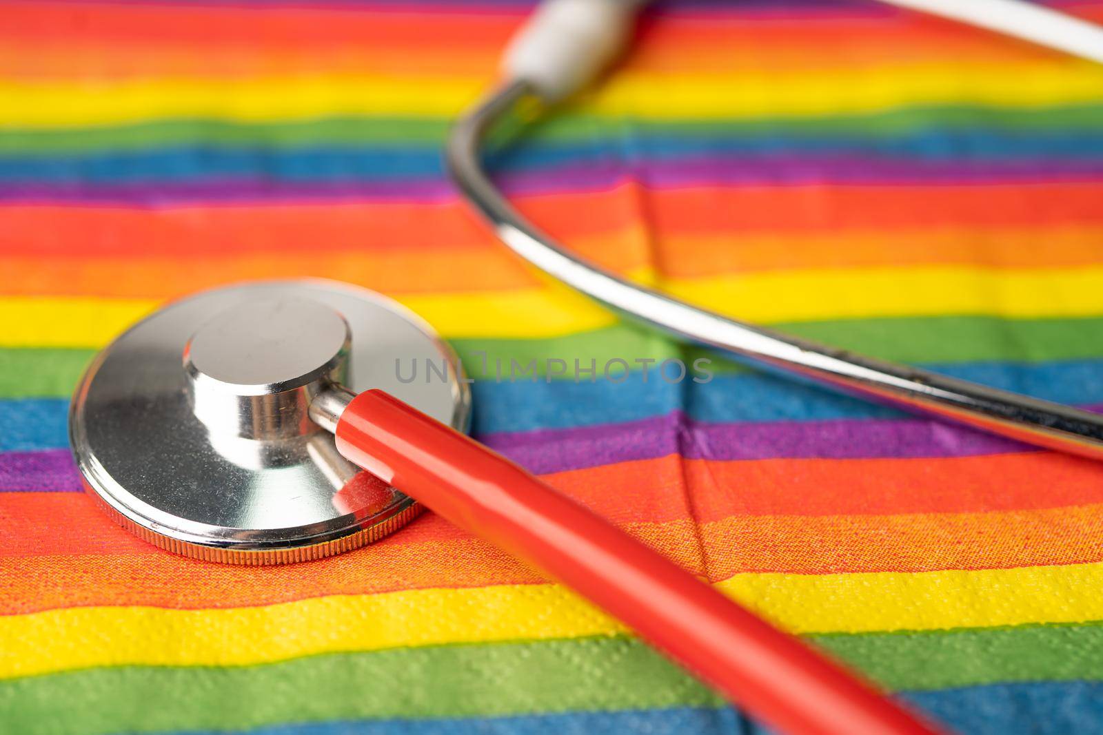 Black stethoscope on rainbow flag background, symbol of LGBT pride month celebrate annual in June social, symbol of gay, lesbian, bisexual, transgender, human rights and peace.