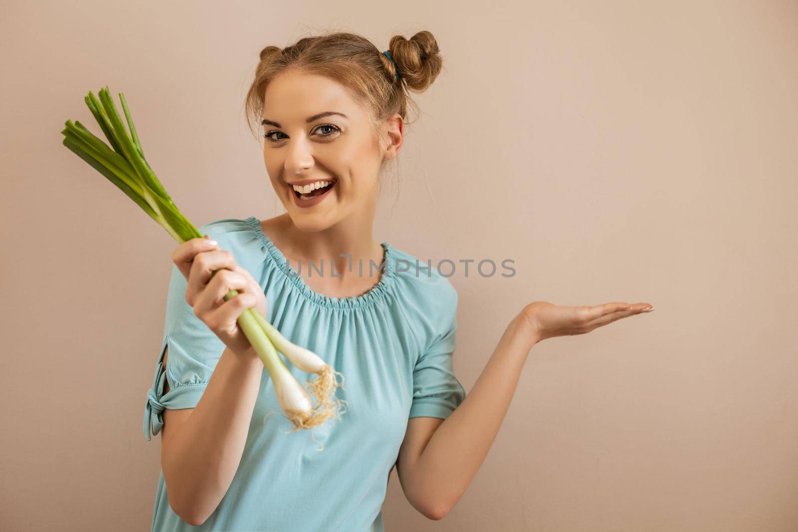Portrait of happy cute woman holding young onion and gesturing.Toned image.