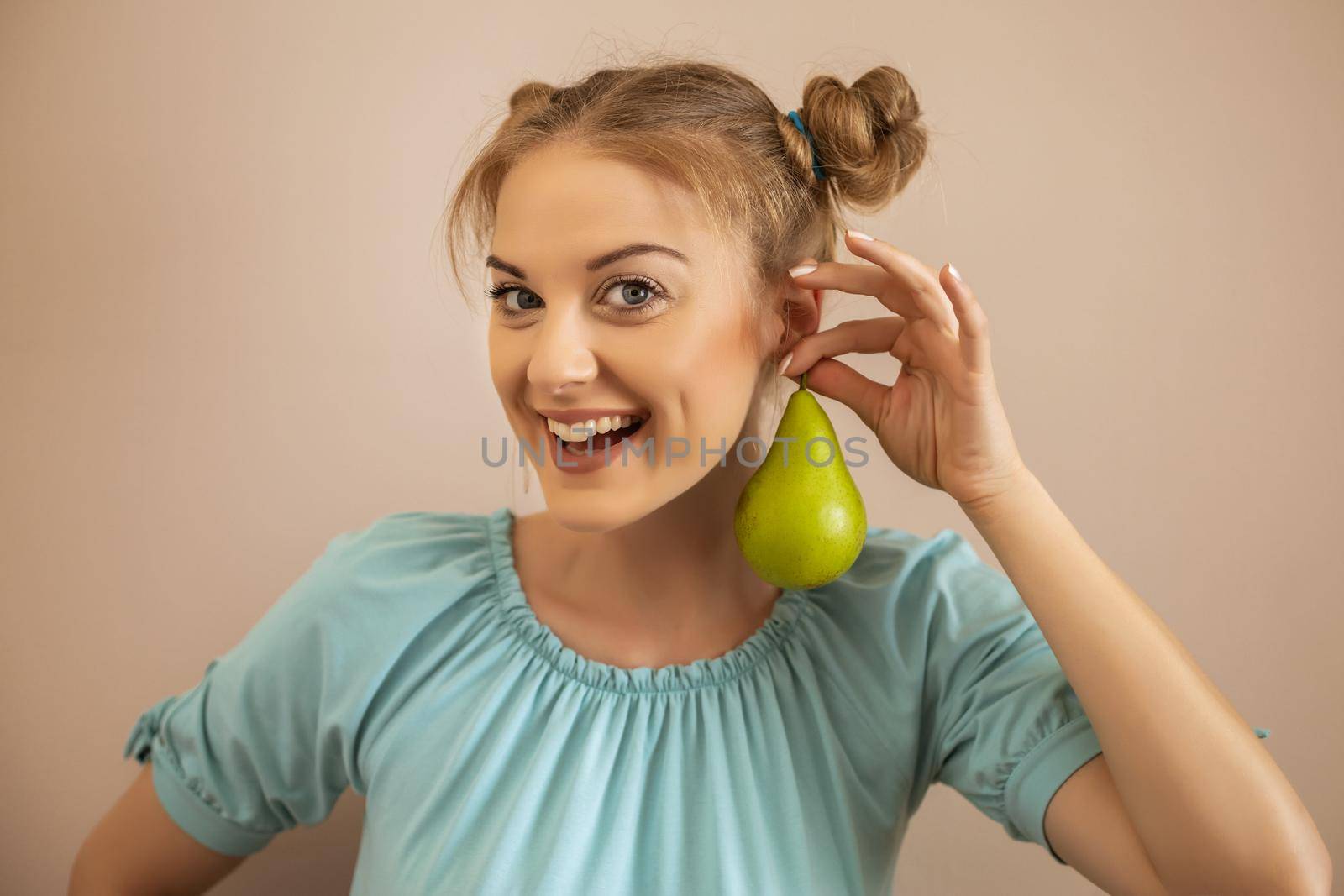 Portrait of playful cute woman holding pear.Toned image.
