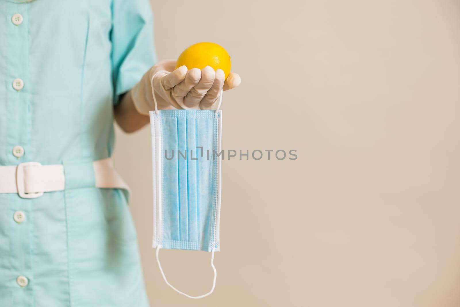 Image of medical nurse holding surgical mask and lemon.