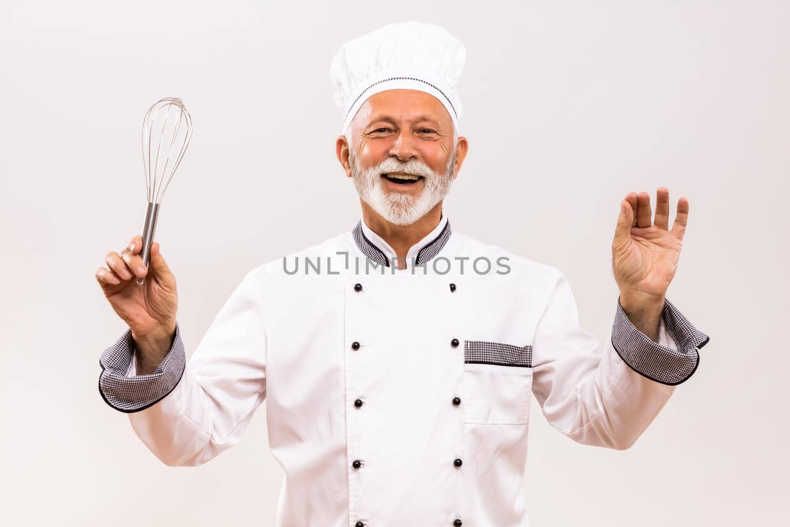 Image of  musical conductor senior chef with wire whisk on gray background.