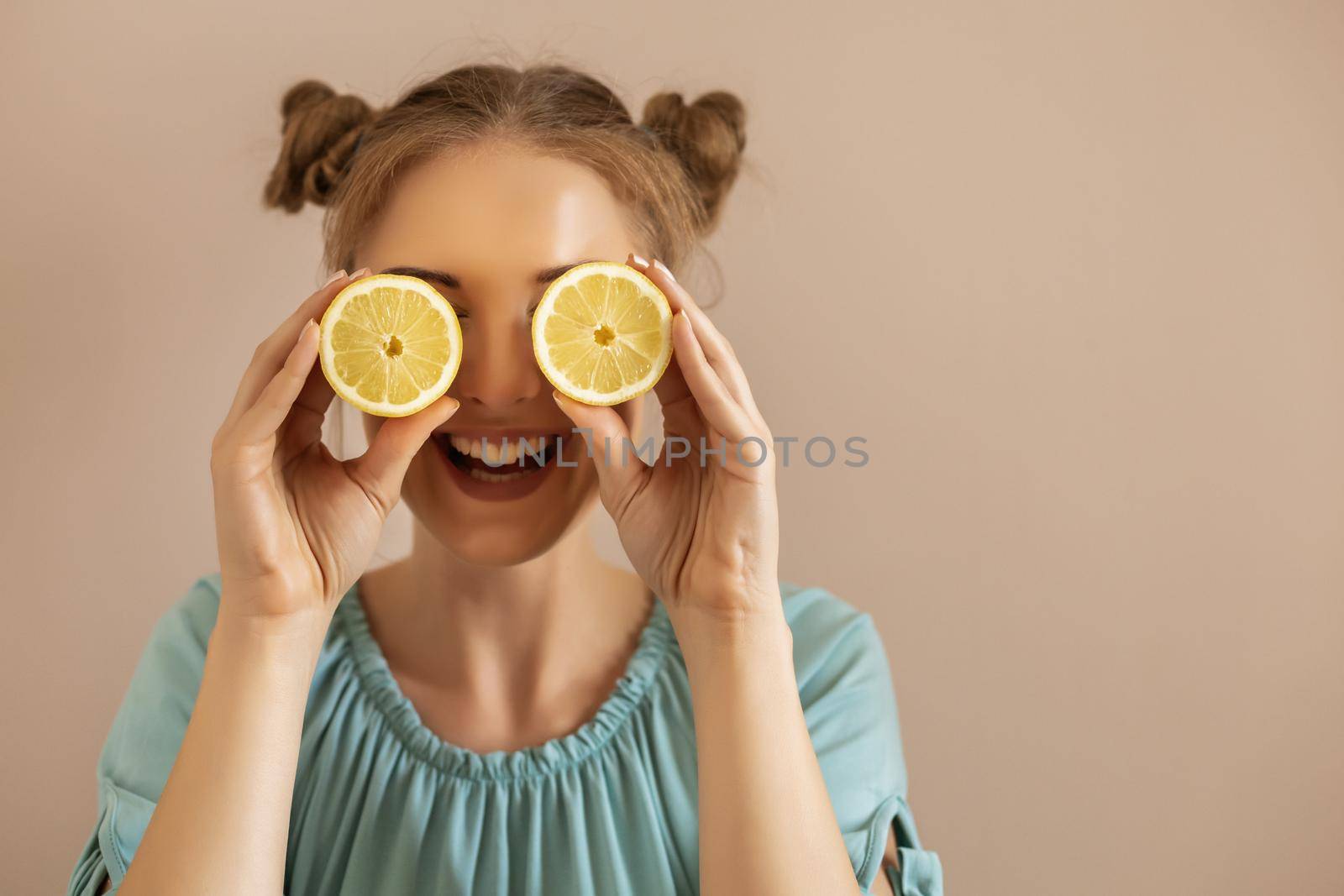 Cute woman is covering her eyes with slices of lemon.Toned image.