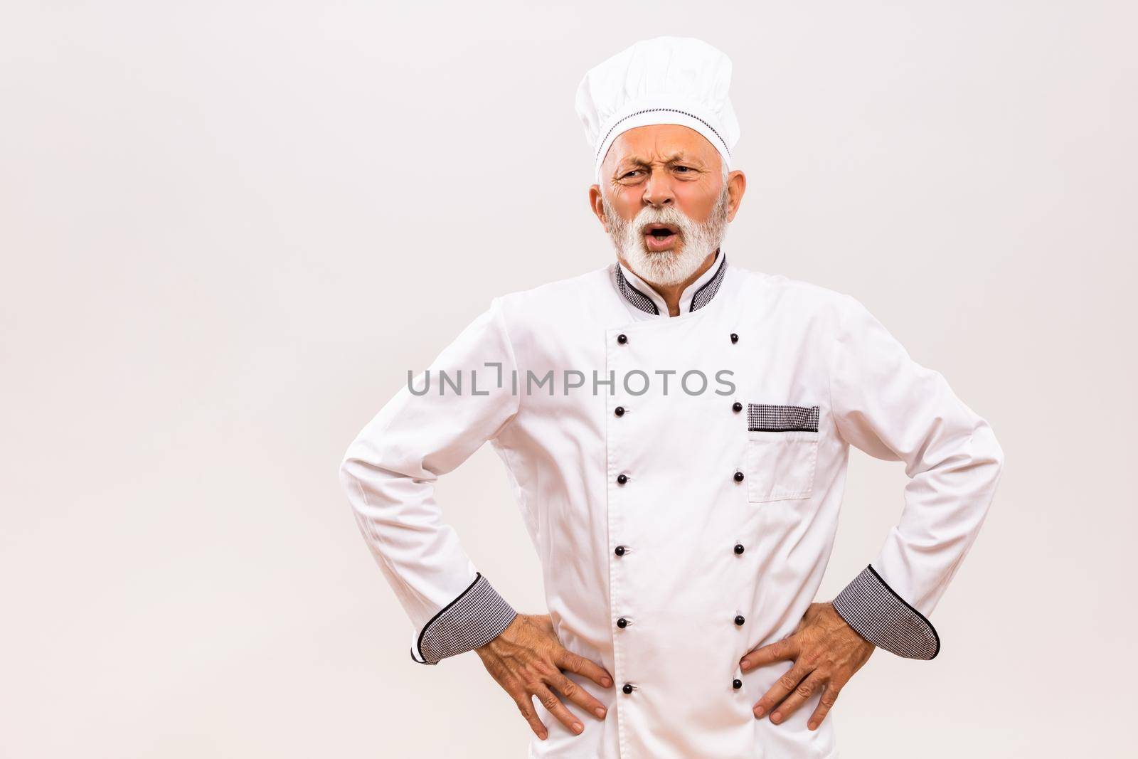 Image of exhausted senior chef on gray background.