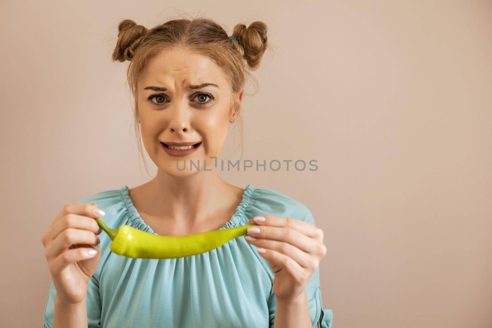 Woman is grimacing while holding  chilli green pepper by Bazdar