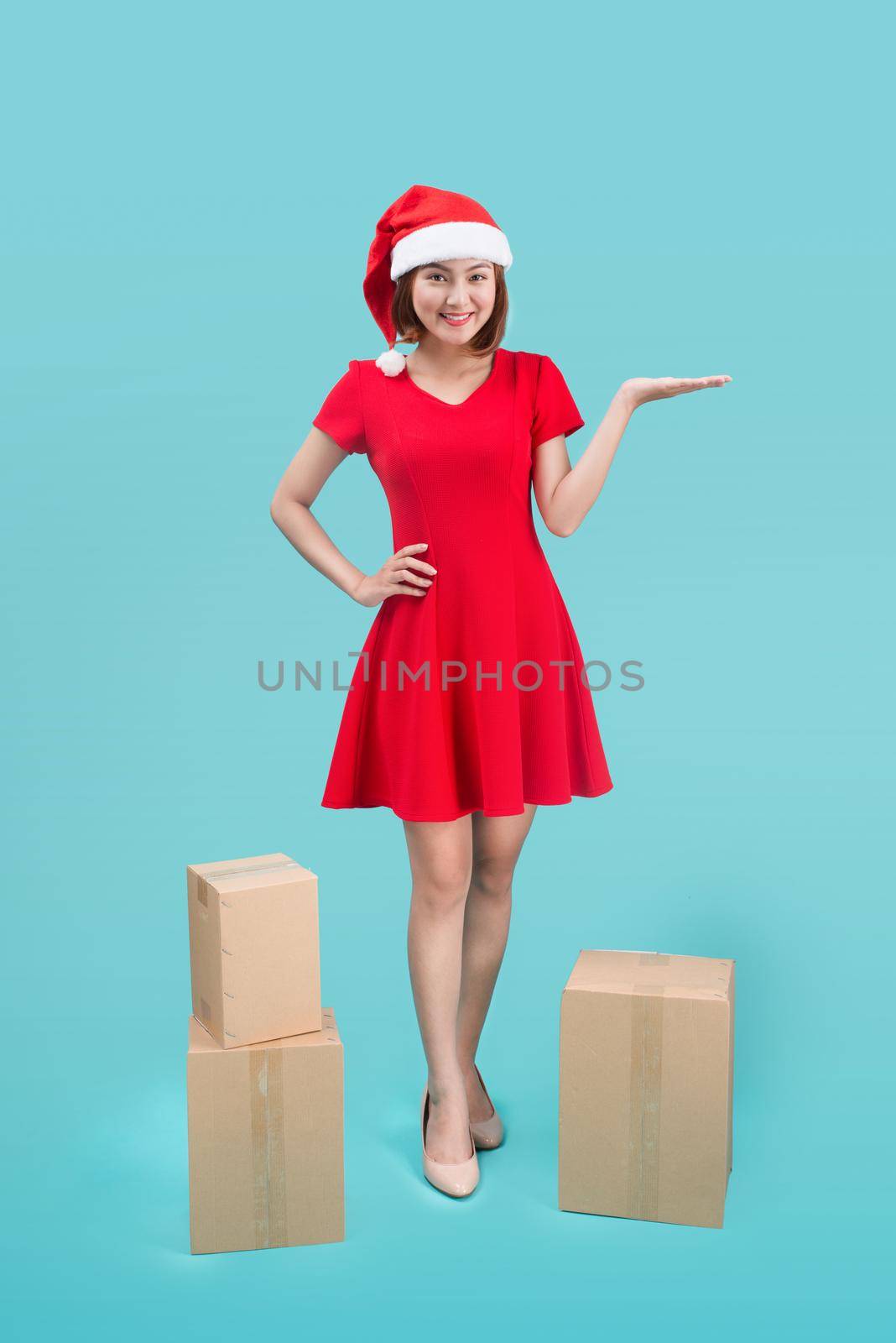 Full-body of attractive cheerful asian girl in Santa's hat pointing with her hand at copy space and happy smiling