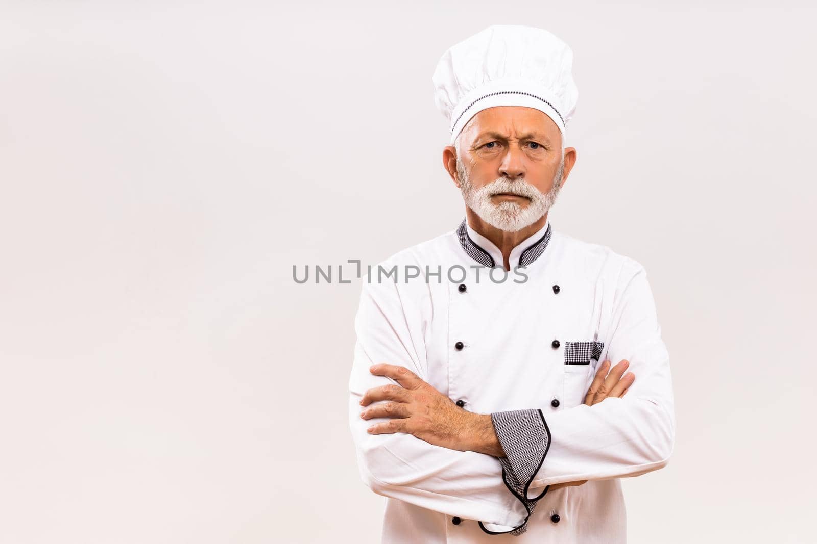 Portrait of angry senior chef  on gray background.
