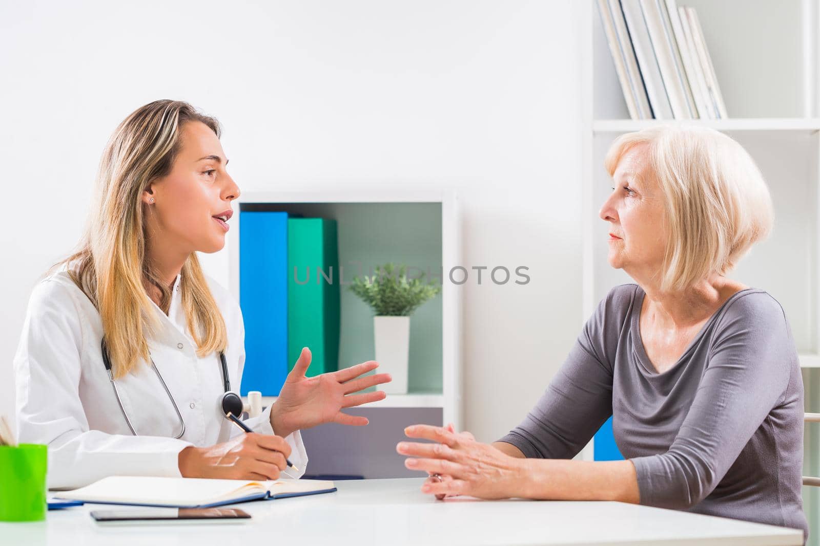 Female doctor and senior woman patient talking in doctor's office