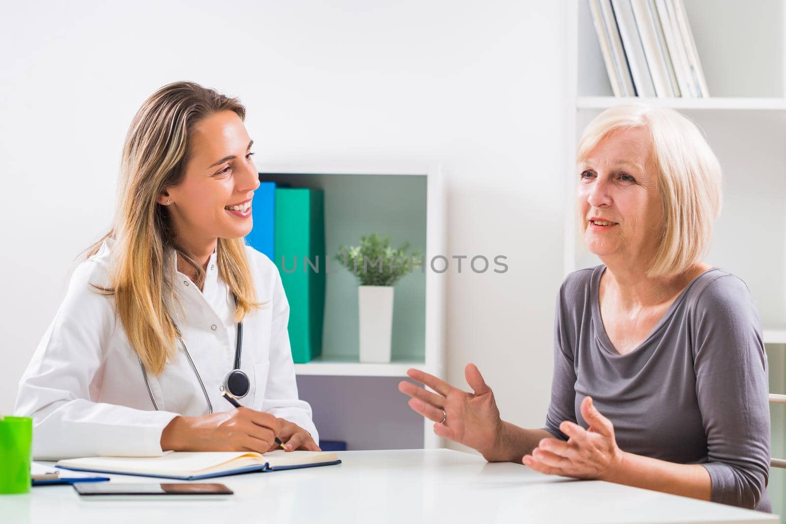 Female doctor and senior woman patient talking in doctor's office