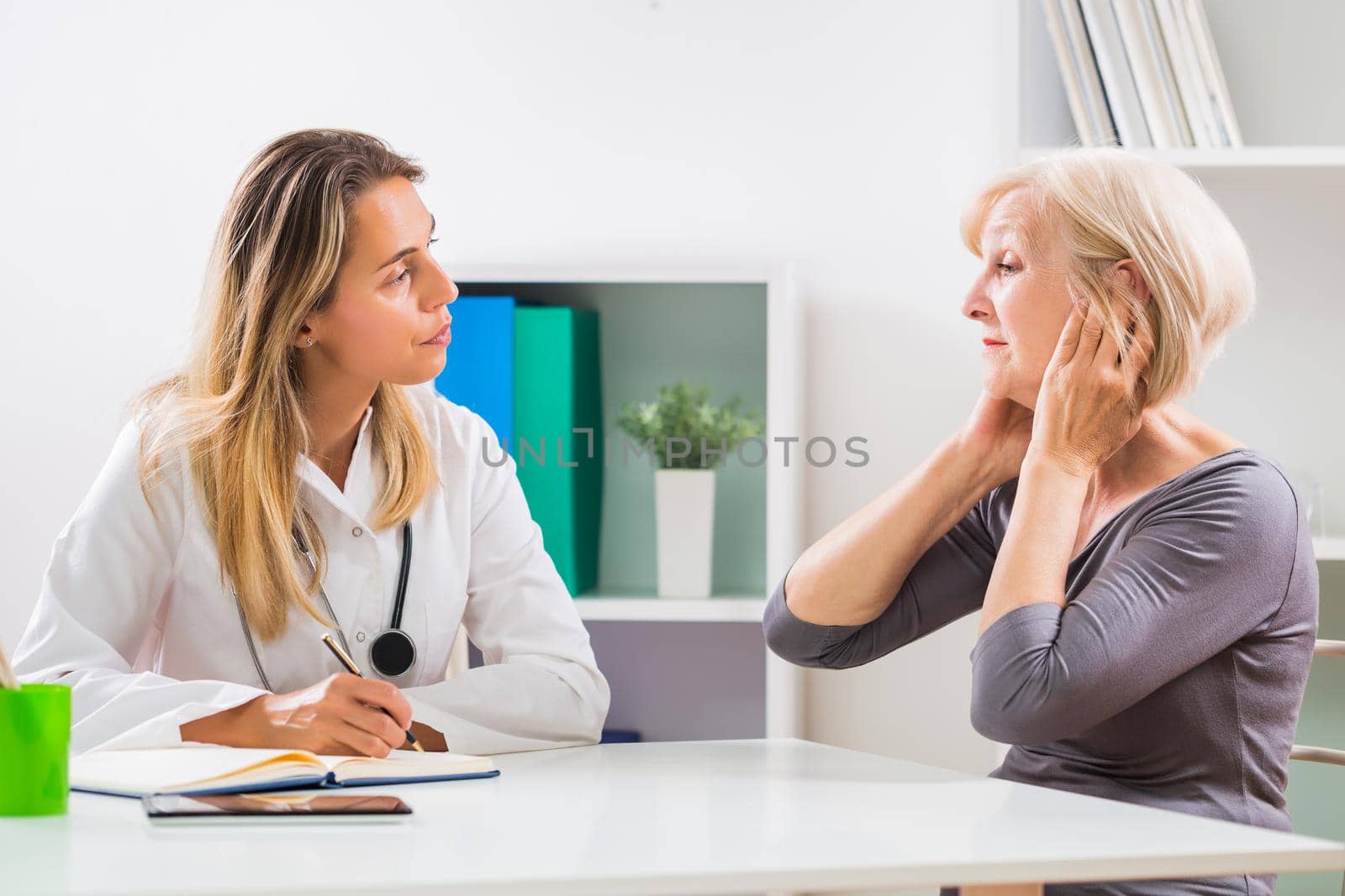 Senior patient telling female doctor how she is having problems with her ears.