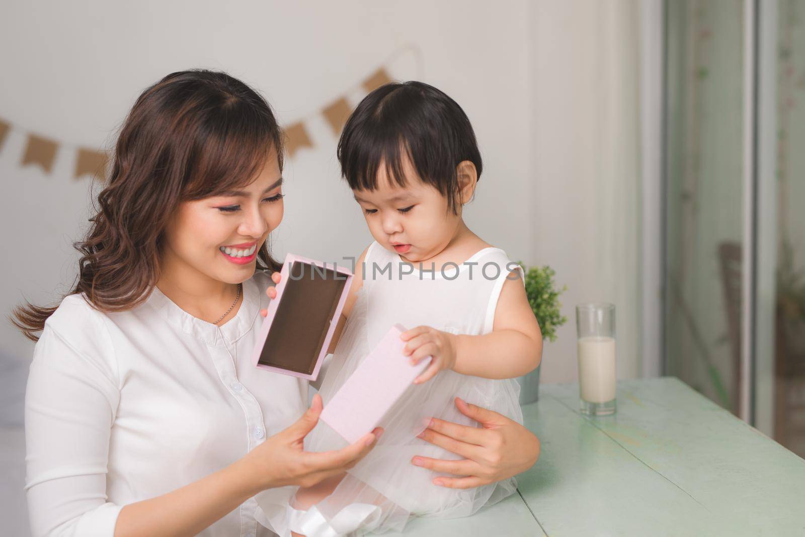 Happy family, beautiful young mother with her adorable little daughter open gift box