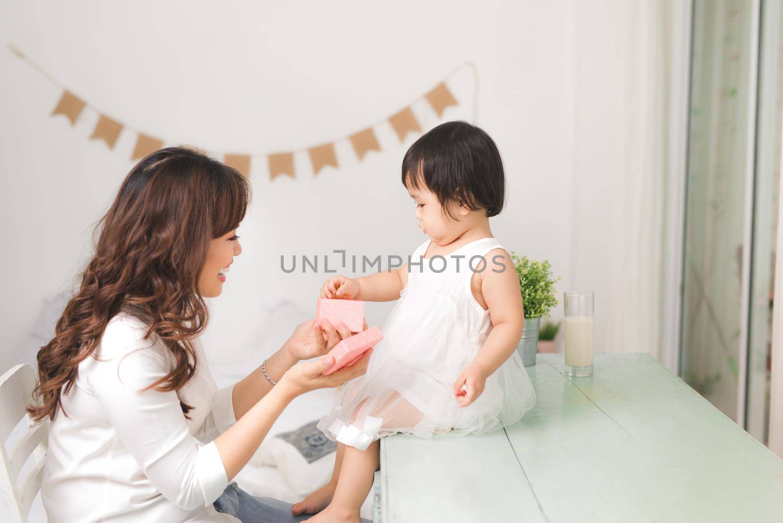 Happy family, beautiful young mother with her adorable little daughter open gift box