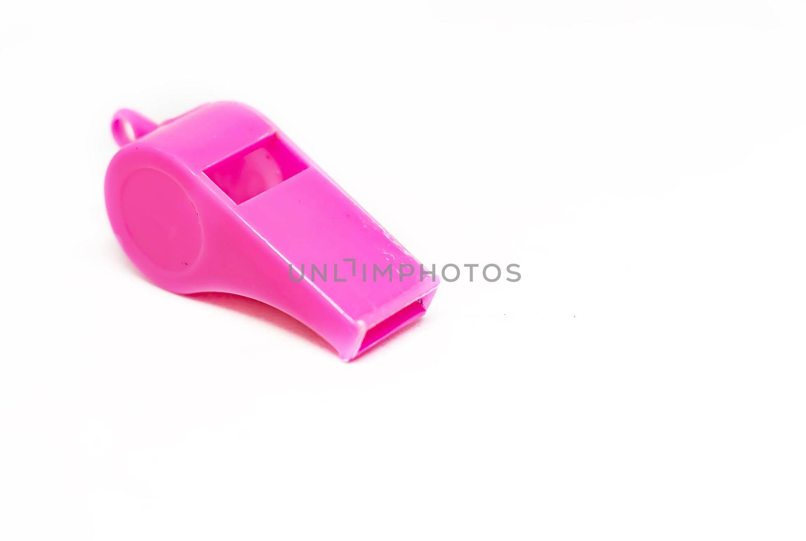 A pink plastic whistle isolated on a white background. Tool for sport and training. Warning and shrill sound