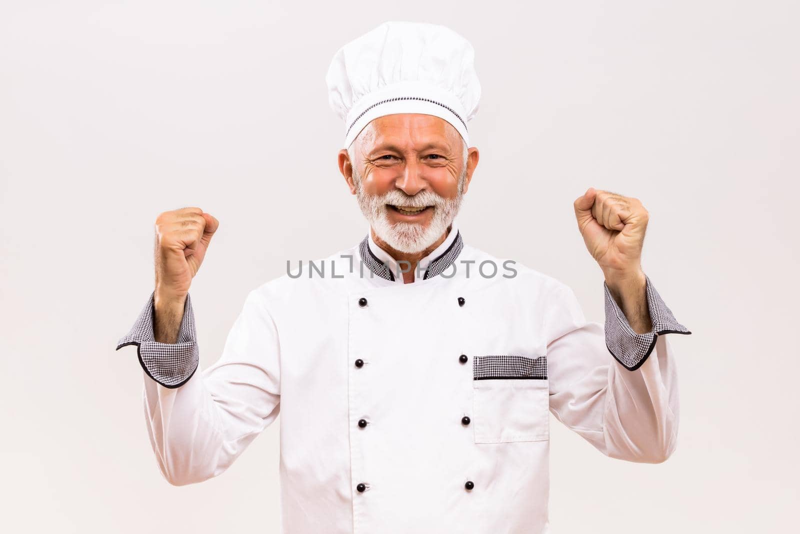Portrait of  excited senior chef on gray background.