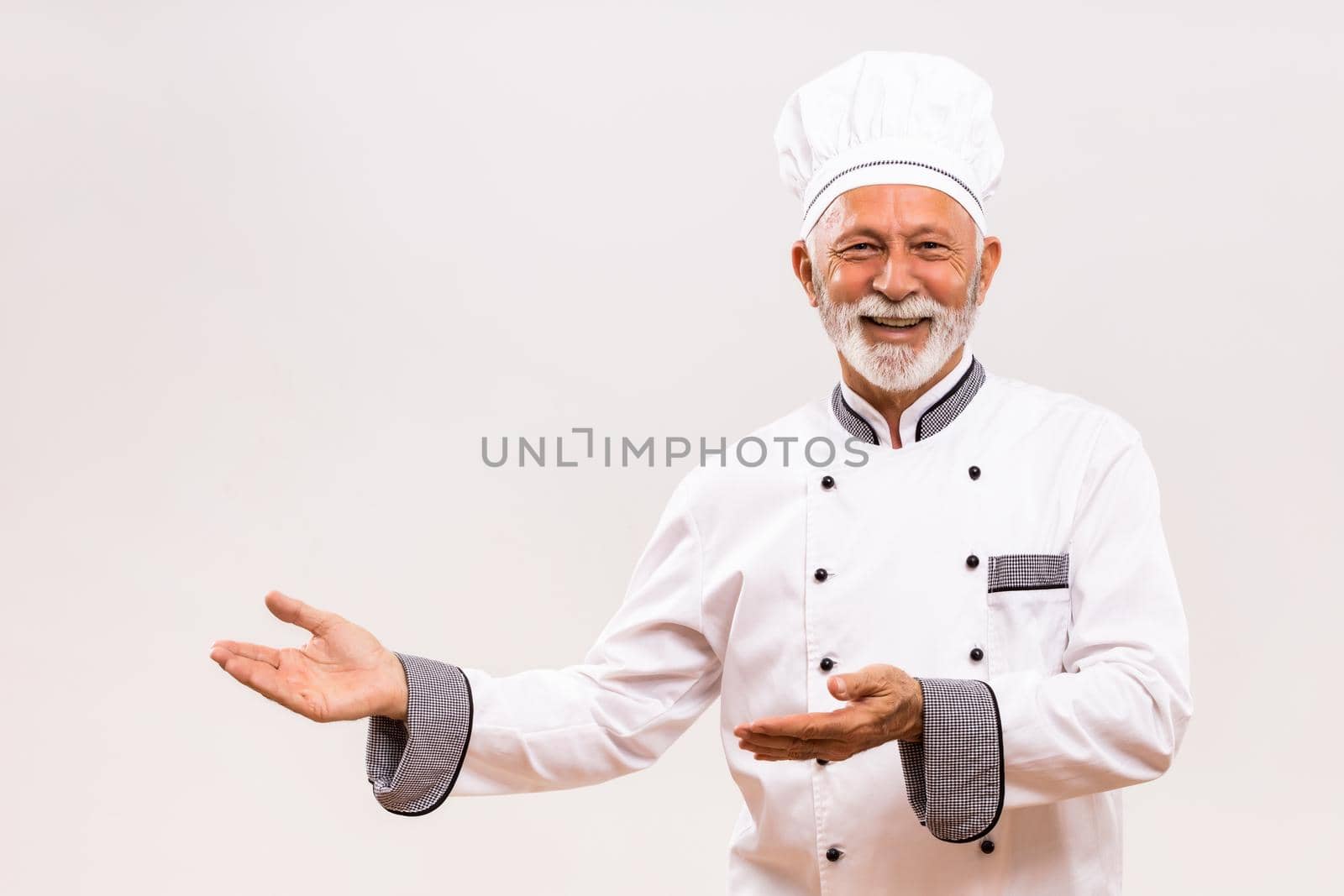 Portrait of senior chef showing welcome gesture.