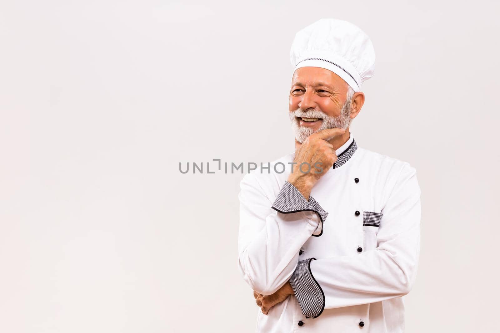 Portrait of senior chef thinking  on gray background.