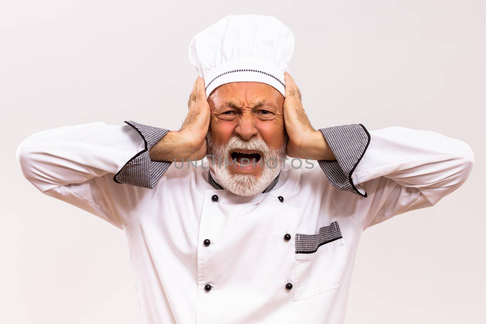 Portrait of  senior chef in panic on gray background.