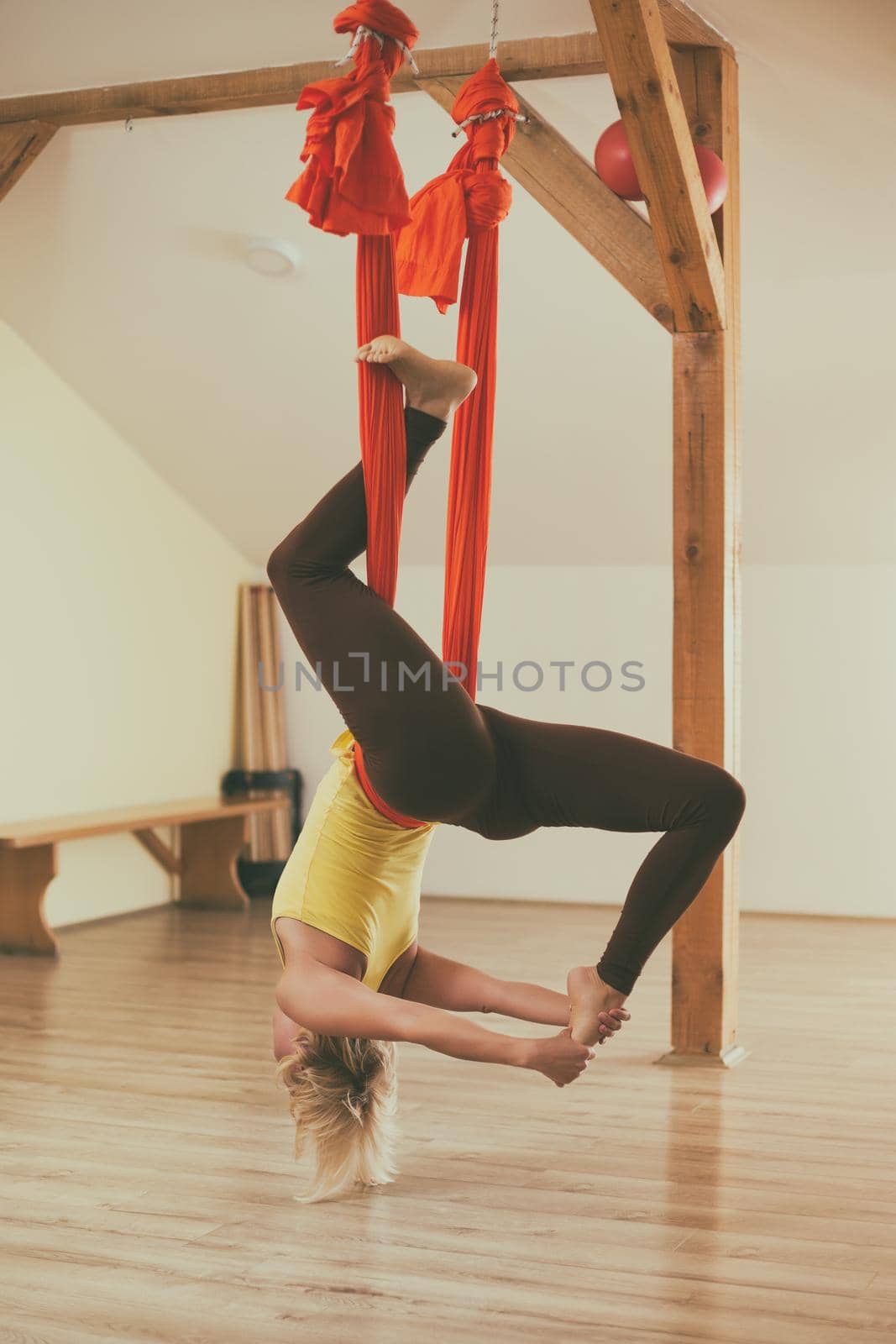 Woman doing aerial yoga in the fitness studio.Image is intentionally toned.