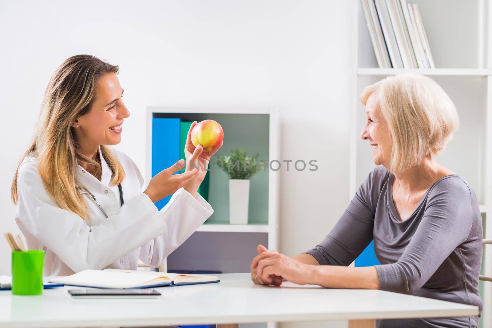Female doctor  giving advice about eating healthy food to her senior woman patient by Bazdar