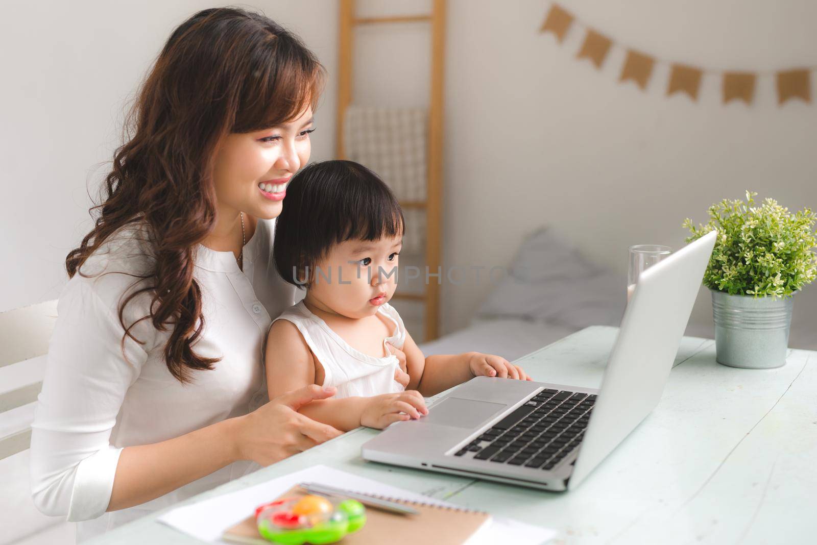 Happy young asian mother and her baby playing games on internet. by makidotvn