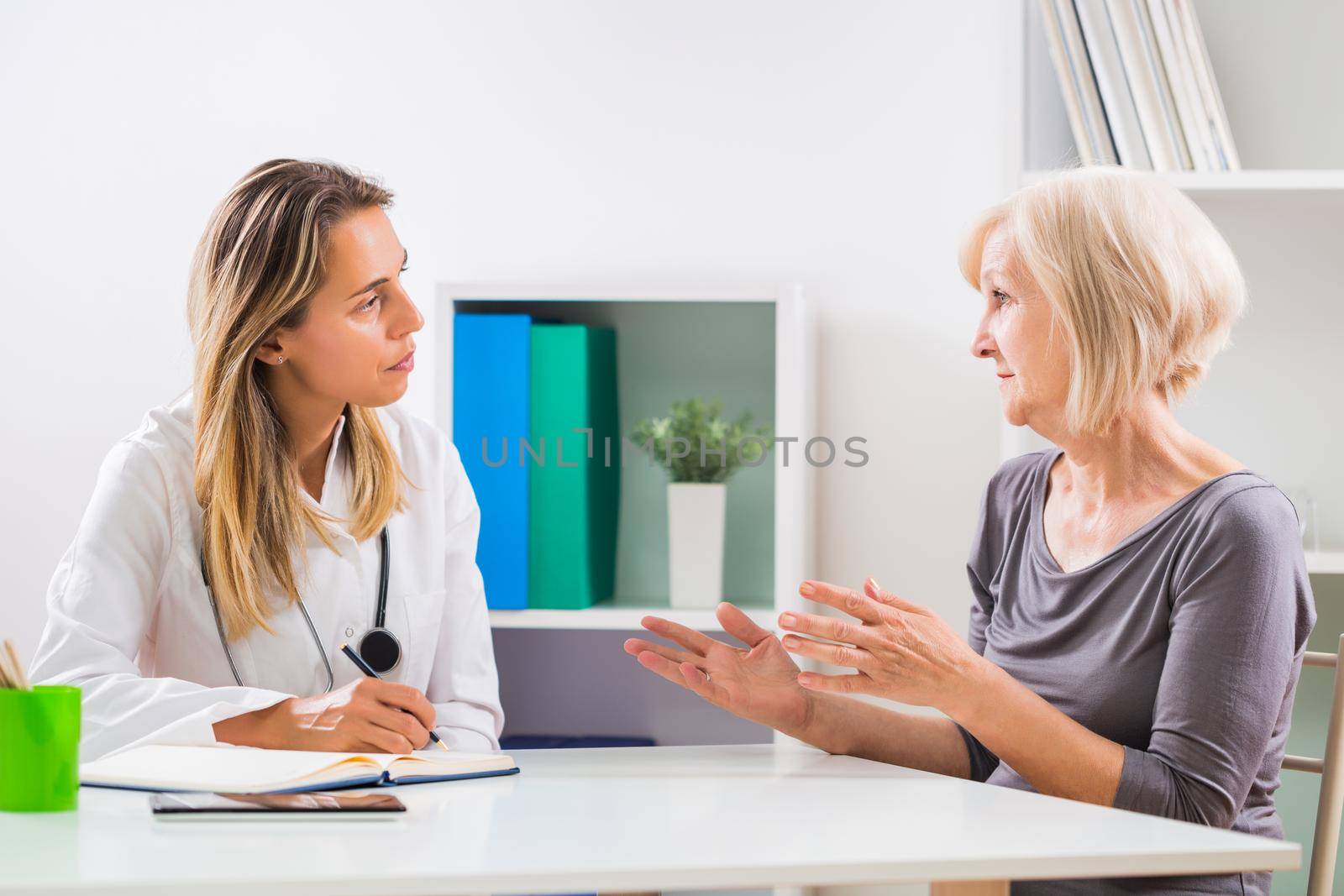 Female doctor and senior woman patient talking in doctor's office.
